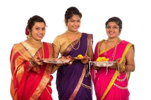 retrato de garotas indianas tradicionais segurando diya e flower thali, irmãs celebrando diwali ou deepavali segurando uma lâmpada de óleo durante o festival em fundo branco foto