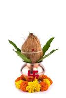 kalash de cobre com coco e folha de manga e pooja thali com diya, kumkum e doces com decoração floral em um fundo branco. essencial no puja hindu. foto