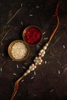 fundo raksha bandhan com um elegante rakhi, grãos de arroz e kumkum. uma pulseira tradicional indiana que é um símbolo de amor entre irmãos e irmãs. foto