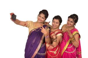 garotas indianas tradicionais tirando selfie com smartphone em fundo branco foto