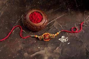 fundo raksha bandhan com um elegante rakhi, grãos de arroz e kumkum. uma pulseira tradicional indiana que é um símbolo de amor entre irmãos e irmãs. foto