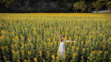 feliz alegre menina asiática com girassol, curtindo a natureza e sorrir no verão no campo de girassol.