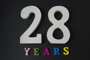 letras e números vinte e oito anos em um fundo preto. foto