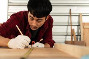 carpinteiro jovem asiático trabalha para clientes meticulosamente, ele é um jovem, um empresário de sucesso e muito habilidoso. foto