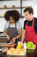 jovem casal está se alimentando enquanto cozinha hambúrguer na cozinha foto