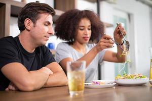 jovem casal está se alimentando enquanto cozinha salada foto