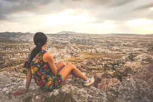 turista mulher feminina em vestido olhando para o dramático vale vermelho com fundo do céu dramático. exploração solo na Turquia. viagem cinematográfica foto