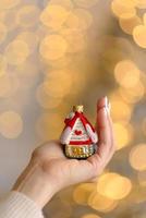 decoração da árvore de natal em forma de casa em uma bela mão feminina foto