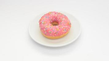 um donut com cobertura rosa no prato fundo branco. Sobremesa doce para o lanche foto