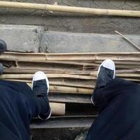 vista de um homem calçando sapatos em um fundo de mastro de bambu foto