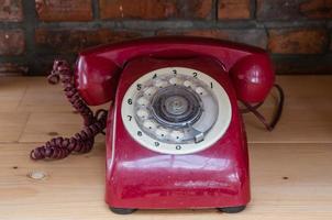 telefone vintage velho vermelho com fundo de mesa de madeira foto
