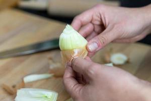 uma pessoa descascando uma cebola de sua casca. preparação da refeição. foto