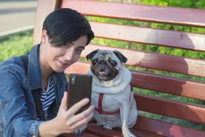 retrato de mulher jovem com cachorro pug no parque foto