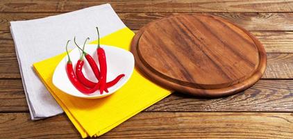tabuleiro vazio e pimenta vermelha em uma mesa vazia foto