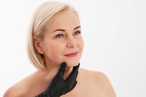 esteticista examina o rosto de uma mulher com rugas da idade - conceito de envelhecimento e cuidados com a pele foto