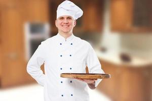 chef sorridente e feliz preparando uma refeição simulada em uma placa de madeira vazia foto