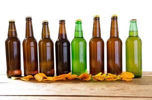 definir garrafas de vidro de cerveja simulada sem rótulo e batatas fritas na mesa de madeira isolada, copie o espaço foto