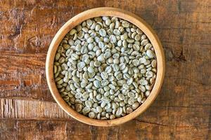 grãos de café verdes não torrados em uma tigela de madeira foto