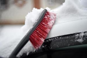 escova de carro vermelha para limpar a neve no inverno na neve foto