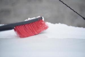 escova de carro vermelha para limpar a neve no inverno na neve foto