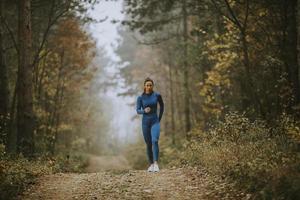 jovem correndo em direção à câmera na trilha da floresta no outono foto