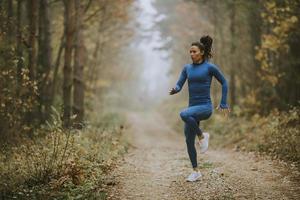 jovem correndo fazendo exercícios na trilha da floresta no outono
