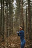 jovem com fato de treino azul alongamento antes do treino na floresta de outono foto