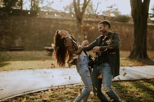 jovem casal se divertindo com folhas de outono no parque foto