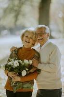 casal sênior com buquê de flores no parque outono foto