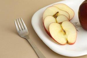 deliciosa maçã e fatia em prato branco com faca e garfo foto