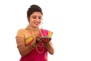 retrato de uma menina indiana tradicional segurando pooja thali com diya durante o festival de luz sobre fundo branco. diwali ou deepavali foto