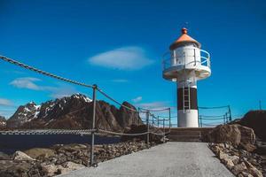 farol no cais no fundo das montanhas e o céu azul nas ilhas lofoten. lugar para texto ou publicidade foto