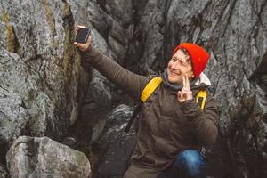 homem viajante tirando auto-retrato com um smartphone no contexto de montanhas e rochas. lugar para texto ou publicidade foto