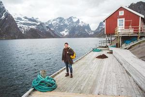 homem viajante com uma mochila de pé em um píer de madeira ao fundo do lago e montanhas nevadas. lugar para texto ou publicidade foto