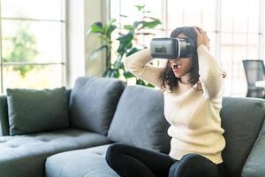 mulher latina usando um fone de ouvido de realidade virtual no sofá