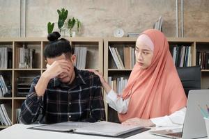 uma jovem parceira de trabalho em startups que é islâmica incentiva e conforta um colega do sexo masculino para que não fique triste e estressado no pequeno local de trabalho, no escritório de comércio eletrônico. foto