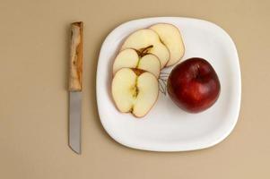 deliciosa maçã e fatia em prato branco com faca e garfo foto