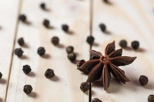 especiarias e ervas. alimentos e ingredientes da cozinha. estrelas de anis e pimenta preta em um fundo de madeira. foto
