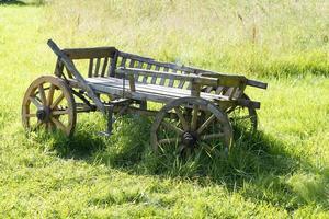 velha carroça de madeira fica na grama. foto