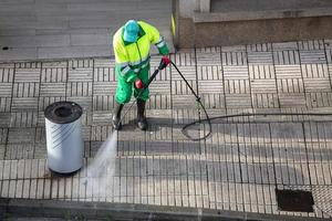 vassoura limpando uma calçada de rua com máquina de jato de água de alta pressão foto