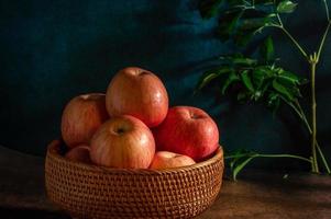 as maçãs no prato parecem pinturas a óleo sob a luz fraca na mesa de grãos de madeira