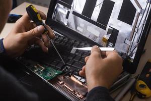 assistente repara laptop com ferramentas e mãos foto