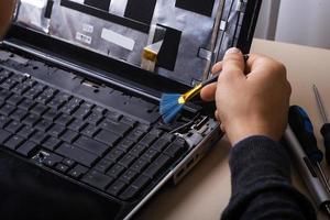assistente repara laptop com ferramentas e mãos foto
