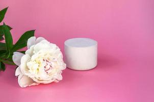 maquete de pódio branco vazio com peônia branca no fundo rosa pastel closeup foto