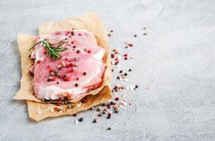 costeletas de porco cruas frescas com especiarias e ervas foto