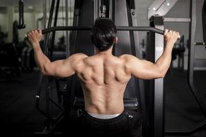 homem fisiculturista com grandes costas musculosas no ginásio foto