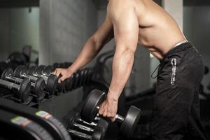 fisiculturista de homem de aptidão muscular é treino com halteres no ginásio foto