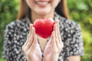 mão de mulher está segurando o conceito de coração vermelho, amor e cuidados de saúde