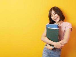 bela mulher asiática estudante universitário feliz em fundo amarelo foto