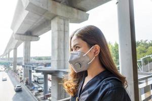 linda mulher usando máscara anti-poeira protege a poluição do ar e pm 2.5 na cidade de rua foto